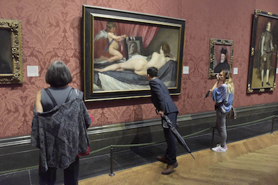 People looking at paintings in the National Gallery while taking a guided tour.