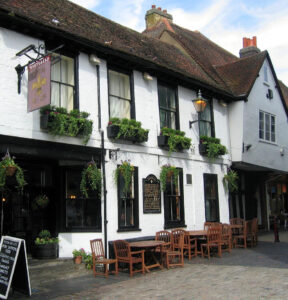 Exterior of the Fleur de Lys pub in St Albans, a traditional English coaching inn with whitewashed walls, hanging flower baskets and outdoor seating