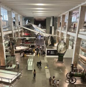 Elevated view across the Science Museum’s main gallery, with historic aircraft, motorcars, steam engines and other technological exhibits on display.